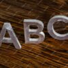 word-abc-with-white-metal-letters-standing-up-dark-brown-wood-background-with-selective-focus_636705-2665